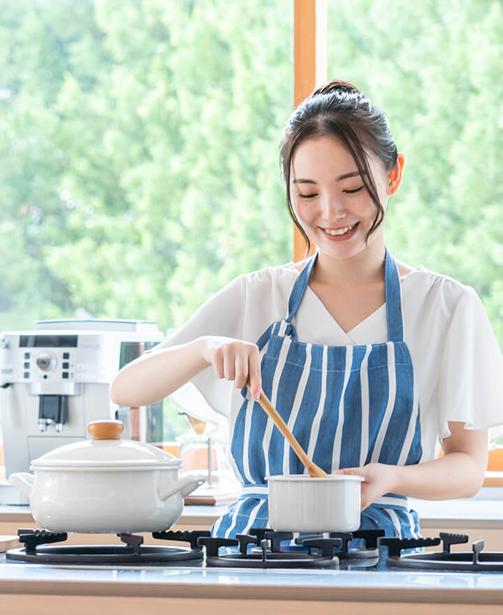 キッチンで藤蔵商店の家電製品を使って笑顔で料理をする女性